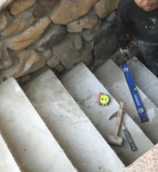 A man using a hammer while working on stairs, showcasing construction expertise for Greater Mansion's remodeling services.