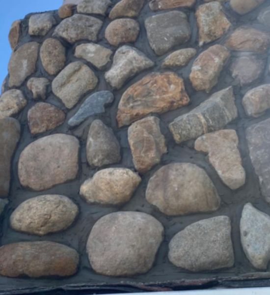 An intricate stone wall composed of different rocks reflects the superior building design and construction services of Greater Mansion.