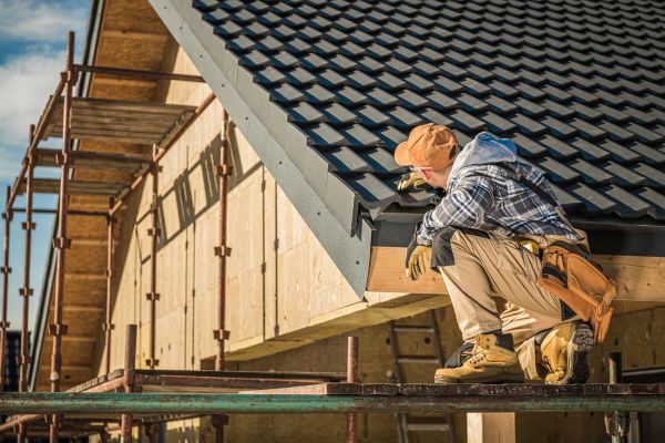 A man in a hard hat works on a roof, showcasing Greater Mansion's expertise in roofing services in Brooklyn, NY.