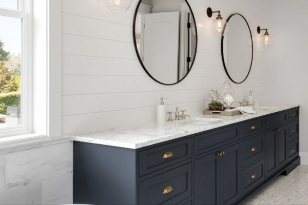 Stylish bathroom with two round mirrors and a contemporary sink, reflecting the quality of Greater Mansion's remodeling services in Brooklyn.