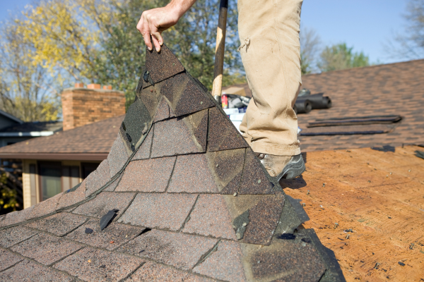 A skilled worker applies shingles to a residential roof in Brooklyn, NY, representing Greater Mansion's construction services.