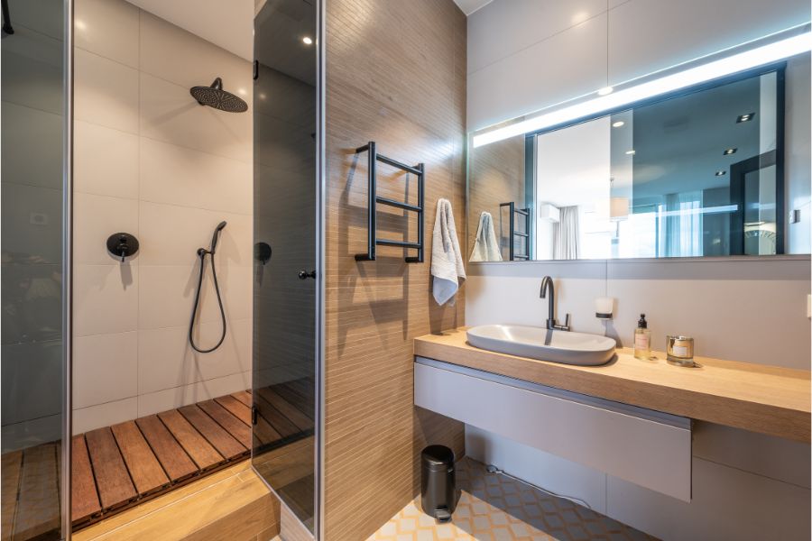 A contemporary bathroom featuring wooden floors and a sleek shower, designed by Greater Mansion in Brooklyn.