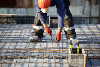 A construction worker diligently pouring concrete on a slab, showcasing expertise in building design and general contracting.